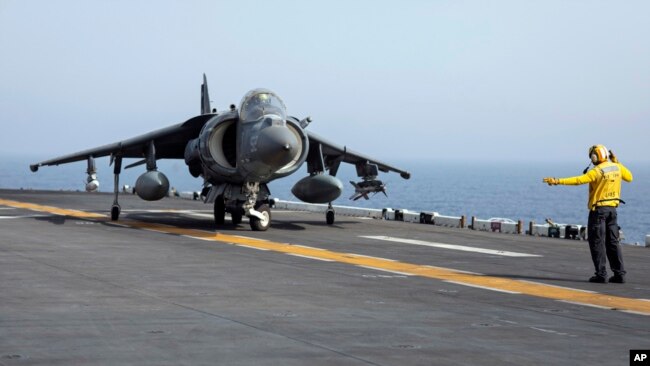 FILE - A US sailor on the amphibious assault ship USS Bataan directs a Marine Corps AV-8B Harrier II jet in the Gulf of Oman.