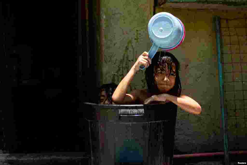 Children take a bath in a bucket during a hot day in Manila, Philippines.