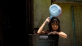 Children take a bath in a bucket during a hot day in Manila, Philippines.