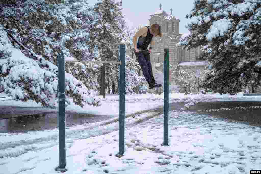 A man exercises on an outdoor gym equipment at Tasmajdan Park during rare spring snowfall, in central Belgrade, Serbia.