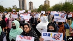 FILE - Afghan refugees hold placards during a rally protesting U.S. visa processing delays, in Islamabad, Pakistan, Feb. 26, 2023.