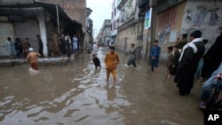 Youngsters wade through a flooded street caused by heavy rain in Peshawar, Pakistan, April 15, 2024.