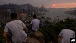 Mainland Chinese tourists look at sunset from a hill in Hong Kong, April 26, 2023.