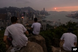 Mainland Chinese tourists look at sunset from a hill in Hong Kong, April 26, 2023.