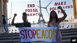 Climate activists Patience Nabukalu of Uganda, left, and Mitzi Jonelle Tan of the Philippines participate in a demonstration ahead of the Global Climate Finance Summit, June 21, 2023 in Paris. 