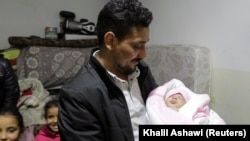 Khalil Al-Sawadi, paman dari bayi perempuan yang lahir saat gempa mematikan awal bulan ini, menggendongnya, di Kota Jandaris yang dikuasai pemberontak, Suriah, 18 Februari 2023. (Foto: REUTERS/Khalil Ashawi)