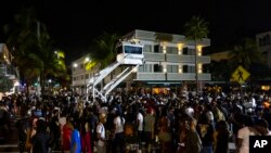 Crowds gather at Ocean Drive and 8th during spring break in Miami Beach, Florida, March 18, 2023. Miami Beach officials imposed a curfew beginning Sunday night after two fatal shootings and rowdy, chaotic crowds that police have had difficulty controlling. 