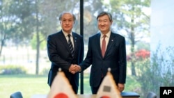 In this photo provided by South Korea Presidential Office, Takeo Akiba, left, Japan's National Security Adviser shakes hands with Cho Tae-yong, South Korean National Security Adviser, right, in Seoul, South Korea, May 3, 2023. 