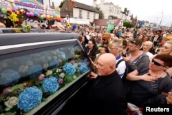 A hearse carrying the coffin of late Irish singer Sinead O'Connor passes by during her funeral procession as fans line the street to say their last goodbye to her, in Bray, Ireland, Aug. 8, 2023.