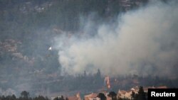 A helicopter drops water on a wildfire in Los Calpes, Spain, March 24, 2023.