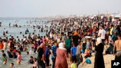 Palestinian family members displaced by the ongoing war with Israel seek relief from heat along the Mediterranean Sea at Khan Younis beach, Gaza Strip, May 20, 2024.