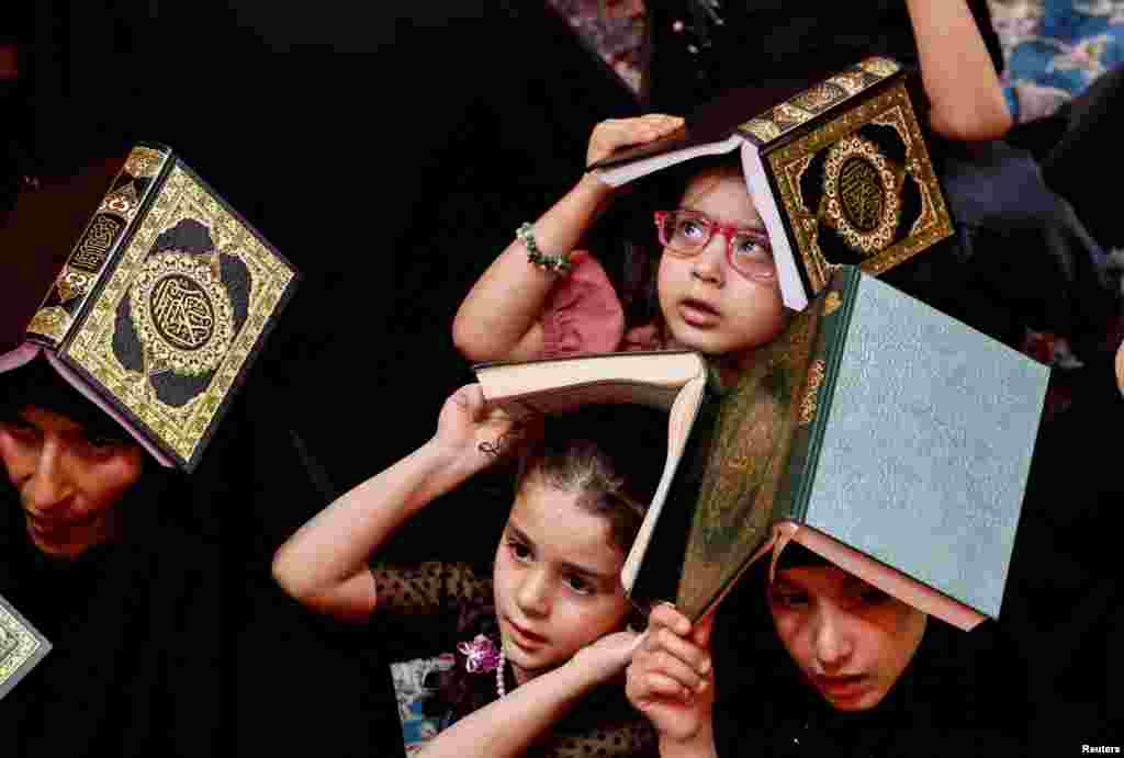 Shiite worshipers place copies of the Quran on their heads during the holy month of Ramadan at Imam Ali Shrine in Najaf, Iraq, April 9, 2023.