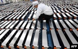 This photo taken on March 12, 2021 shows a worker with car batteries at a factory for Xinwangda Electric Vehicle Battery Co. Ltd, which makes lithium batteries for electric cars and other uses, in Nanjing in China's eastern Jiangsu province.