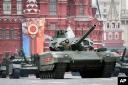 A Russian Armata tank, foreground rolls along Red Square during a rehearsal for the Victory Day military parade in Moscow, Russia, Sunday, May 6, 2018.