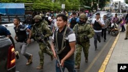 Soldiers and police provide security behind an armored vehicle as supporters of presidential candidate Daniel Noboa, of the National Democratic Action Alliance political party, attend a rally with their candidate in downtown Esmeraldas, Ecuador, Oct. 6, 2023. 