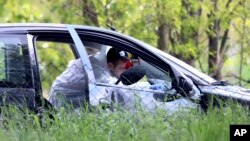 Policijski forenzičar uzima dokaze iz automobila u selu Dubona, 50-ak kilometara južno od Beograda, u petak, 5. maja 2023, nakon druge masovne pucnjave u dva dana.