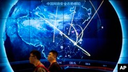 FILE - Attendees walk past a display showing cyberattacks in China at the China Internet Security Conference in Beijing, on Sept. 12, 2017. (AP Photo/Mark Schiefelbein, File)