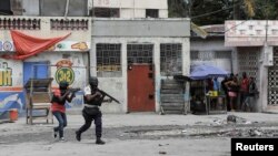 FILE - People huddle in a corner as police patrol the streets after gang members tried to attack a police station, in Port-au-Prince, Haiti, April 25, 2023. An escalation of armed violence has worsened food insecurity and a cholera outbreak in Haiti, according to UNICEF.