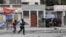 FILE - People huddle in a corner as police patrol the streets after gang members tried to attack a police station, in Port-au-Prince, Haiti, April 25, 2023. An escalation of armed violence has worsened food insecurity and a cholera outbreak in Haiti, according to UNICEF.