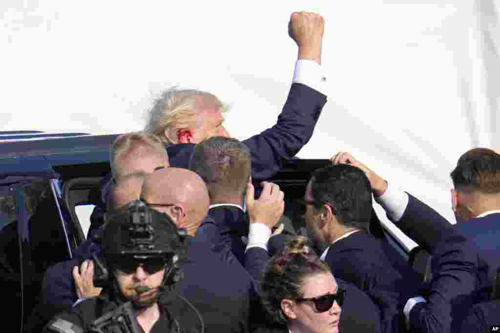 Donald Trump raises his fist as he is helped off the stage.