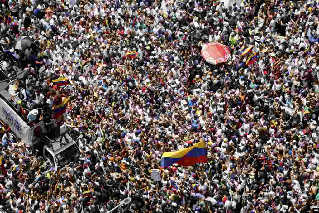 Opposition leader Maria Corina Machado, lower right, waves a Venezuelan national flag, during a rally to protest official results that declared President Nicolas Maduro the winner of the July presidential election, in Caracas, Aug. 17, 2024.