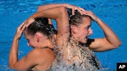 FILE - Maryna Aleksiiva and Vladyslava Aleksiiva of Ukraine compete in the duet free routine final of the artistic swimming at the 19th FINA World Championships in Budapest, Hungary, June 23, 2022.