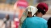 印度一名男子冒着酷暑抱着一个头上披着遮阳毛巾的幼儿走在查谟市大街上。（2024年6月2日）
