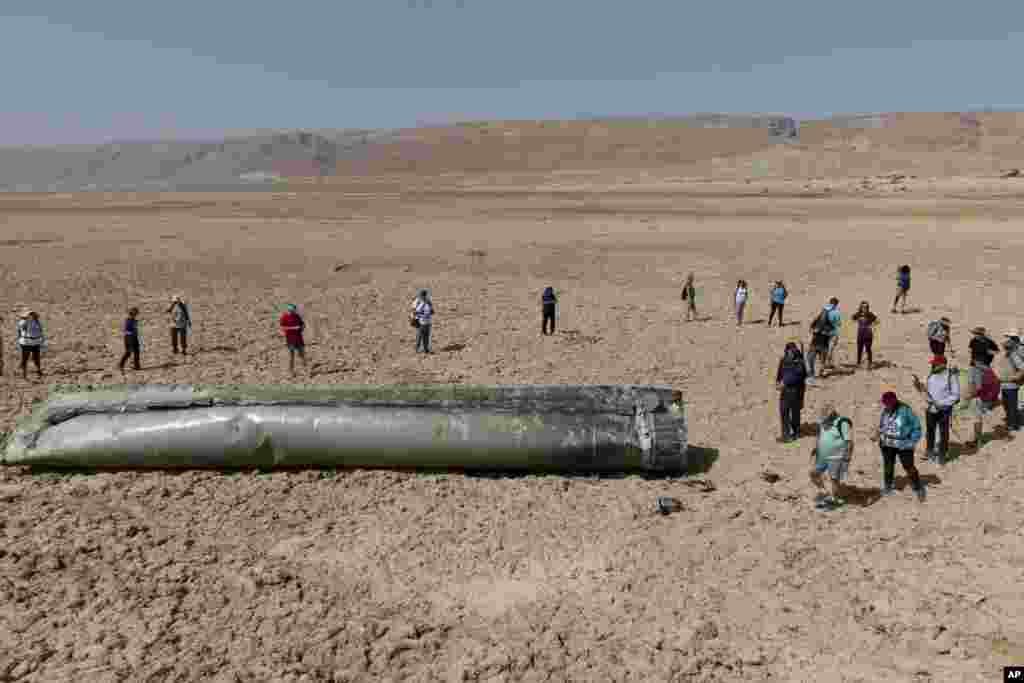 People gather around a component from an intercepted ballistic missile that fell near the Dead Sea in Israel, April 20, 2024. 