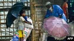 FILE - Rohingya refugees wait at a food distribution place during monsoon rainfall in Kutupalong refugee camp in Ukhia, Bangladesh, August 10, 2022.