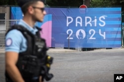 A police officer walks past a 'Paris 2024' Olympics sign at the 2024 Summer Olympics in Paris, July 20, 2024.