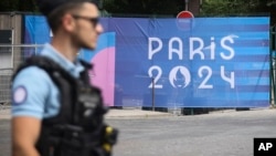 Seorang petugas polisi berjalan melewati spanduk Olimpiade Paris pada Olimpiade Musim Panas 2024, Sabtu, 20 Juli 2024, di Paris, Prancis. (Foto: AP)