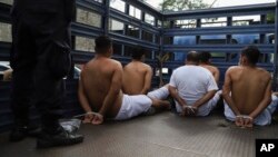 Personas arrestadas por la policía por tener presuntos vínculos con pandillas esperan esposadas con bridas en la parte trasera de un camión para ser trasladadas a una prisión en la Delegación de Policía de San Bartolo en Soyapango, El Salvador, el martes 16 de agosto de 2022.