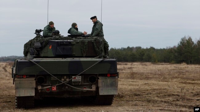 FILE - Ukrainian and Polish soldiers sit on top of a German-made Leopard 2 tank during training at a military base and test range in Swietoszow, Poland, Feb. 13, 2023.
