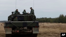 Soldados ucranianos y polacos se sientan encima de un tanque Leopard 2 durante el entrenamiento en una base militar y campo de pruebas en Swietoszow, Polonia, el 13 de febrero de 2023.