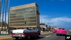 FILE - Tourists in classic cars pass the U.S. Embassy in Havana, Cuba, Oct. 3, 2017. U.S. intelligence agencies cannot link a foreign adversary to any of the incidents associated with “Havana Syndrome” reported by American personnel around the world. 