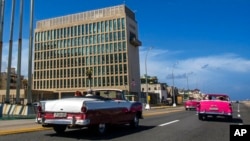 FILE - Tourists in classic cars pass the U.S. Embassy in Havana, Cuba, Oct. 3, 2017. A new study has not been able to link brain injuries with the mysterious “Havana Syndrome” reported by some American diplomats who were posted in Cuba and other countries.