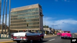 Mobil klasik yang membawa sejumlah turis bergerak melewati gedung Kedutaan Besar AS di Havana, Kuba, pada 3 Oktober 2017. (Foto: AP/Desmond Boylan)