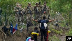 Seorang migran berhadapan dengan sejumlah petugas keamanan Texas di tepi sungai Rio Grande di Meksiko, pada 11 Mei 2023. (Foto: AP/Fernando Llano)