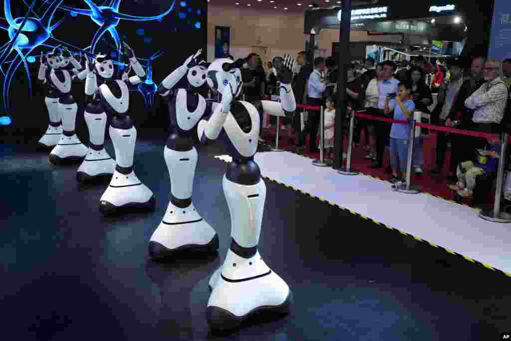 Visitors look at robots perform on stage during the annual World Robot Conference at the Etrong International Exhibition and Convention Center on the outskirts of Beijing, China.