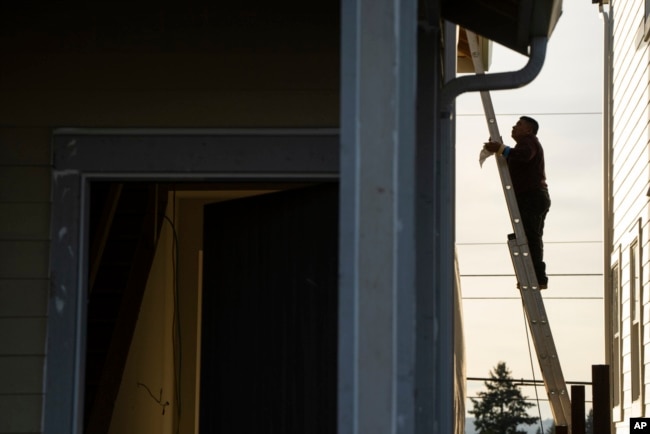 FILE - A worker stands on a ladder while working on a new construction home in Tigard, a suburb of Portland, Oregon, Feb. 22, 2024.