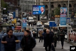 People walk by a billboard showing Turkish President and People's Alliance's presidential candidate Recep Tayyip Erdogan, in Istanbul, April 27, 2023.