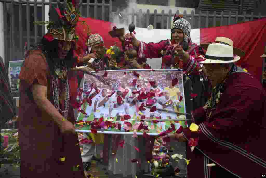 Peruvian shamans hold a poster of Peru&#39;s national soccer team while performing a good luck ritual outside the National Stadium in Lima.