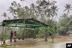 FILE - Two children stand under a roadside shelter to protect from rain before Cyclone Mocha hits in Sittwe, Rakhine State, Sunday, May 14, 2023. (AP Photo, File)