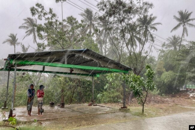 FILE - Two children stand under a roadside shelter to protect from rain before Cyclone Mocha hits in Sittwe, Rakhine State, Sunday, May 14, 2023. (AP Photo, File)