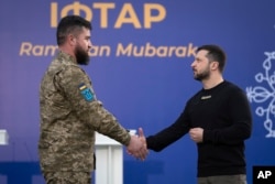 Ukrainian President Volodymyr Zelenskyy, right, awards a Muslim serviceman before an Iftar dinner celebrating Islam's holy month of Ramadan in an Islamic center outside Kyiv, Ukraine, April 7, 2023.