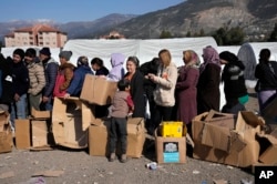 Orang-orang yang kehilangan rumah akibat gempa dahsyat, antre untuk menerima bantuan di kamp darurat, di kota Iskenderun, Turki selatan, Selasa, 14 Februari 2023. (AP/Hussein Malla)