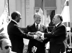 El presidente egipcio Anwar Sadat, el presidente estadounidense Jimmy Carter y el primer ministro israelí Menachem Begin se dan la mano en el jardín norte de la Casa Blanca después de firmar el tratado de paz entre Egipto e Israel en Washington, el 26 de marzo de 1979.