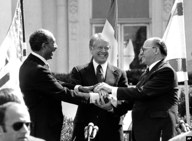 El presidente egipcio Anwar Sadat, el presidente estadounidense Jimmy Carter y el primer ministro israelí Menachem Begin se dan la mano en el jardín norte de la Casa Blanca después de firmar el tratado de paz entre Egipto e Israel en Washington, el 26 de marzo de 1979.