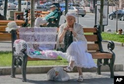 Seorang perempuan duduk di bangku dan merajut saat menikmati hari pada musim gugur yang hangat di Khreshchatyk Avenue, ibu kota Ukraina, Kiev, Kamis, 8 September 2016. (AP/Efrem Lukatsky)