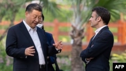 FILE - Chinese President Xi Jinping (L) and French President Emmanuel Macron (R) speak as they visit the garden of the residence of the Governor of Guangdong in Guangzhou, China, on April 7, 2023.
